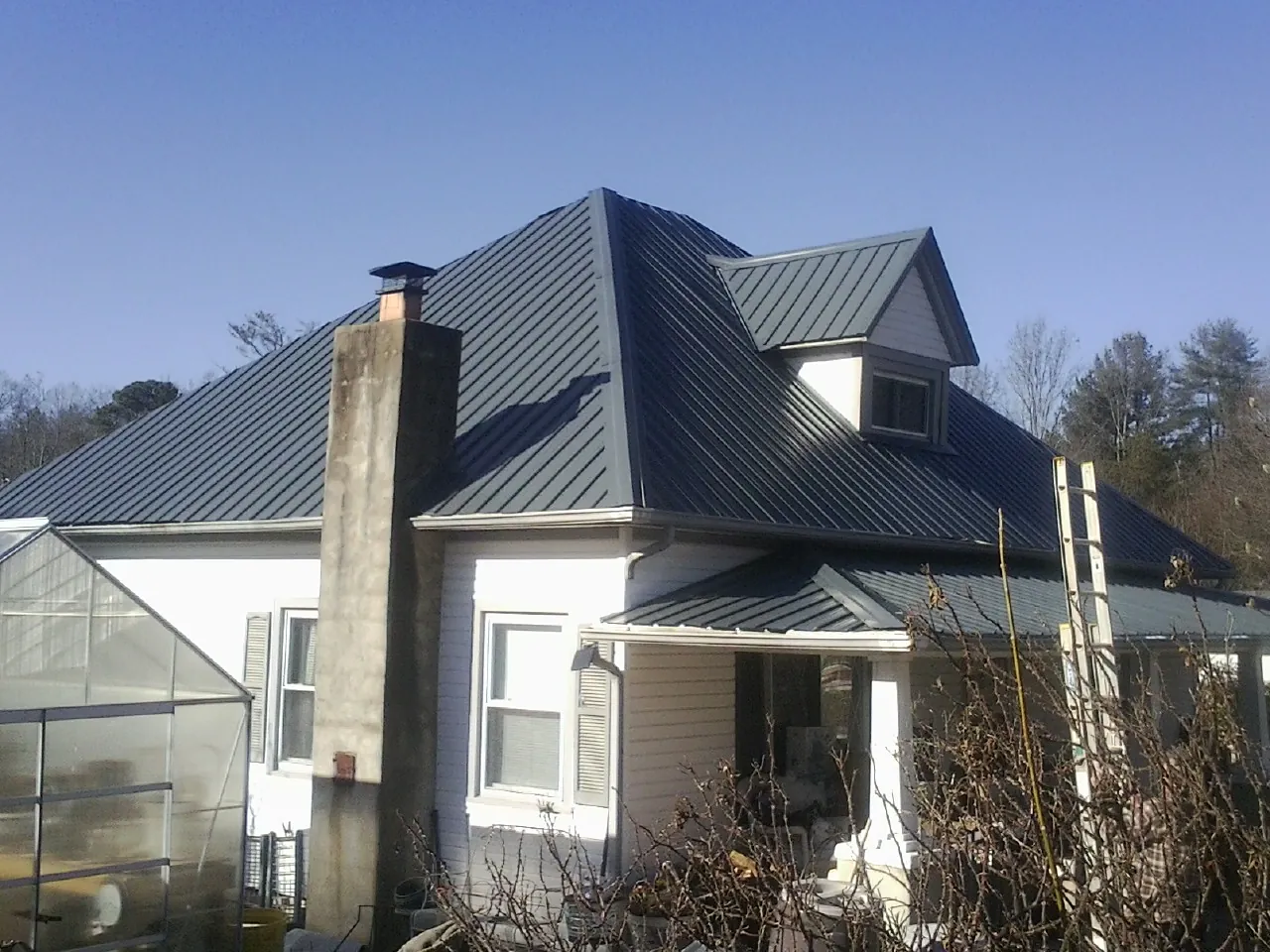 Dark blue standing seam metal roof on a white farmhouse with dormer — Slate & Tile Roof Repair by Roofing Brothers in Sidney