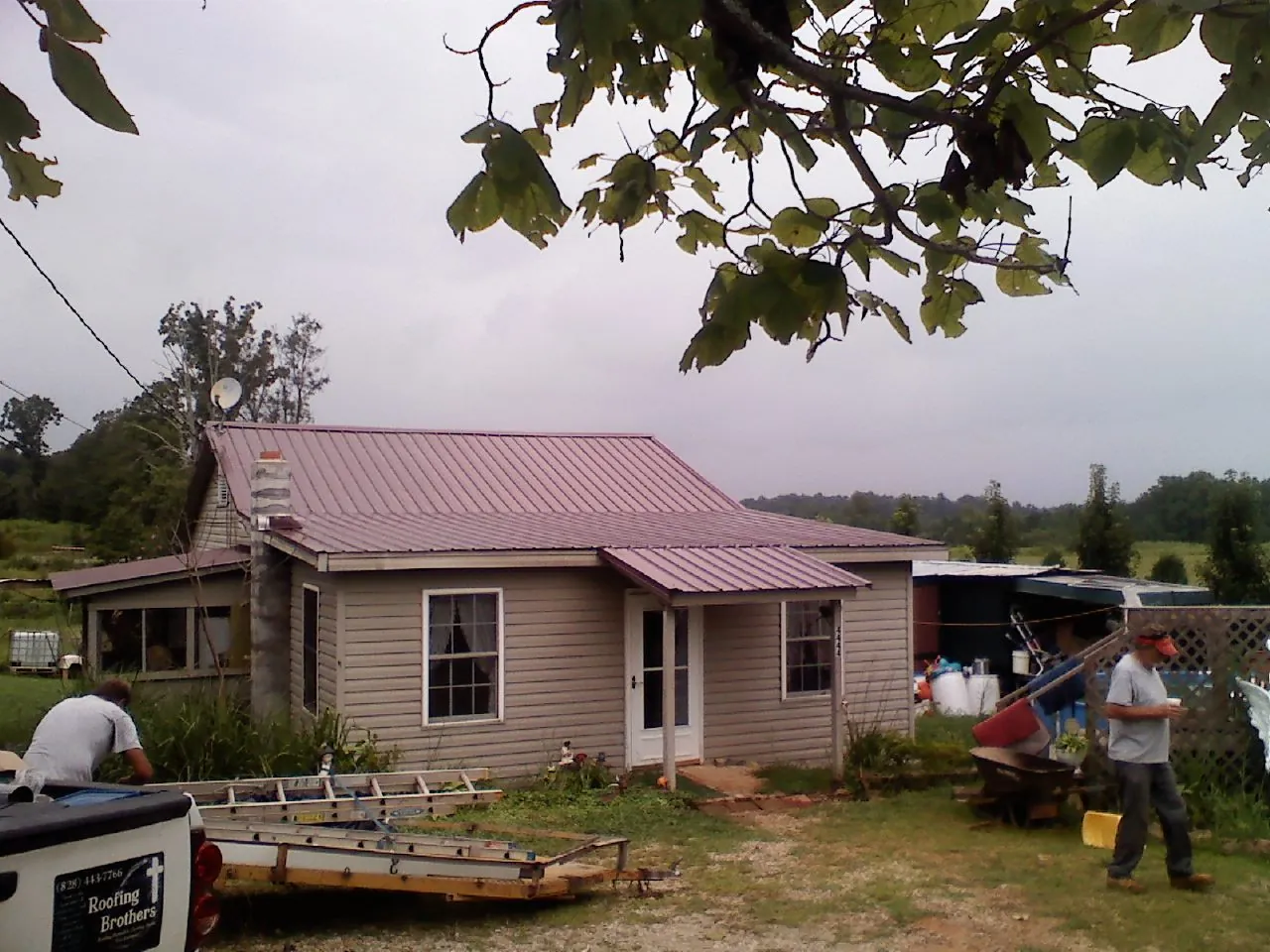 Crew finishing a mauve metal roof on a small farmhouse in Sidney