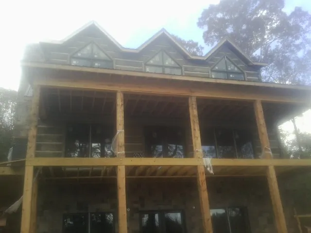 Dormers and porch framing on a large log home under construction — Roof Coating work by our crew in Sidney