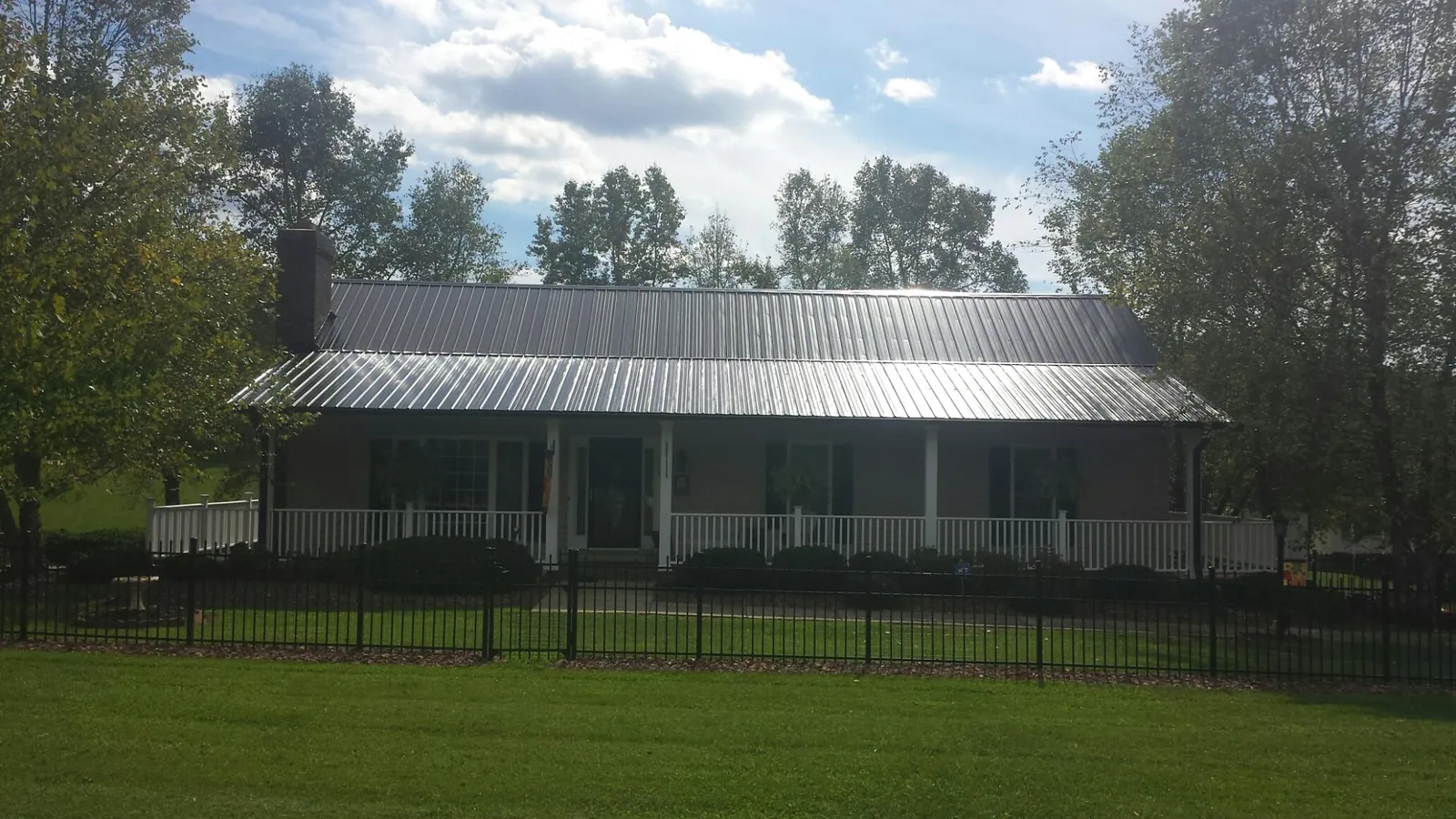 Gray metal roof on a brick ranch with a full width front porch — Gutter Guard Installation work by our crew in Sidney